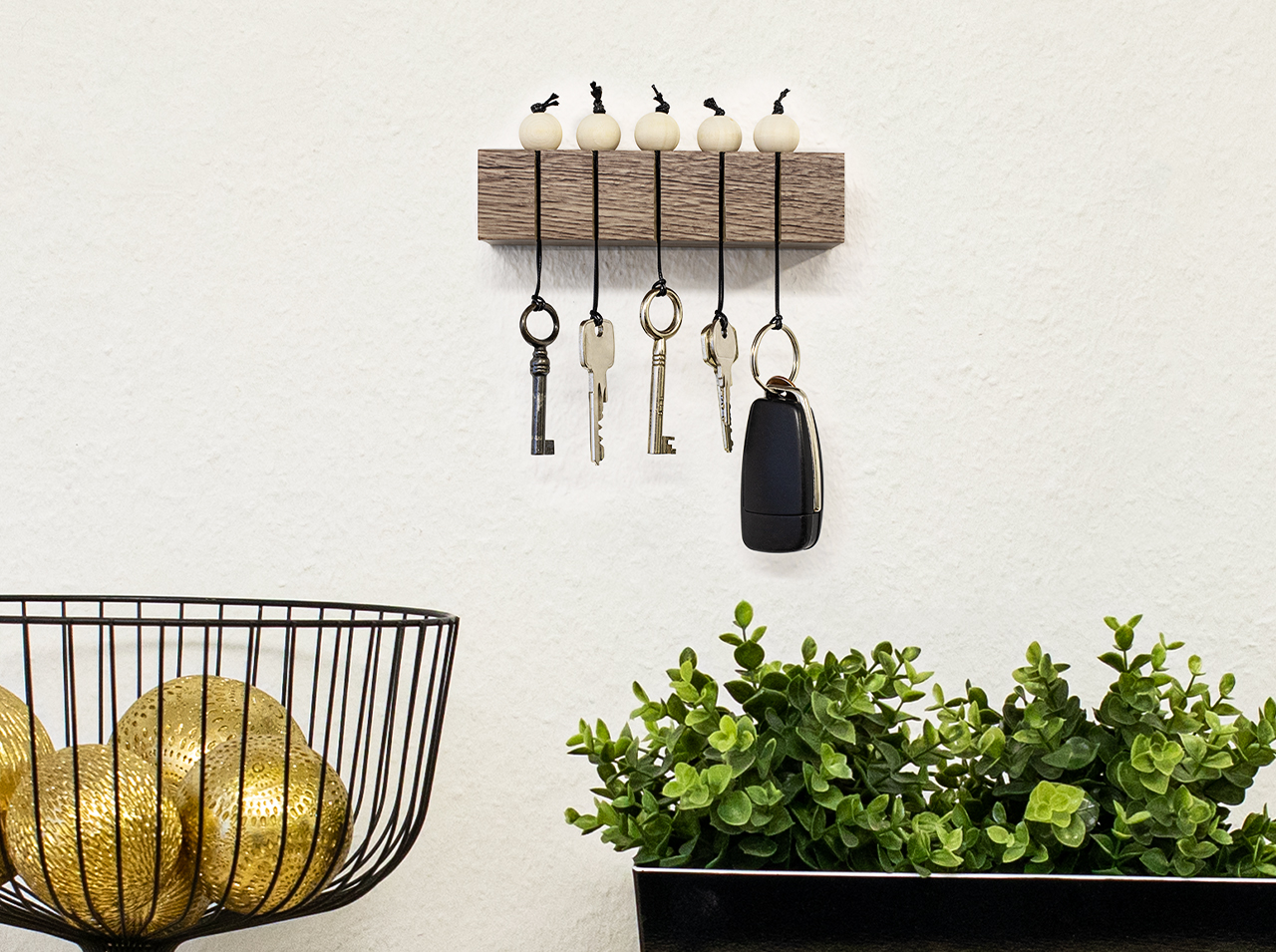 Rectangular key rack in a wood look with the d-c-fix® Sanremo oak sepia adhesive foil and keys hanging on leather straps with wooden balls.