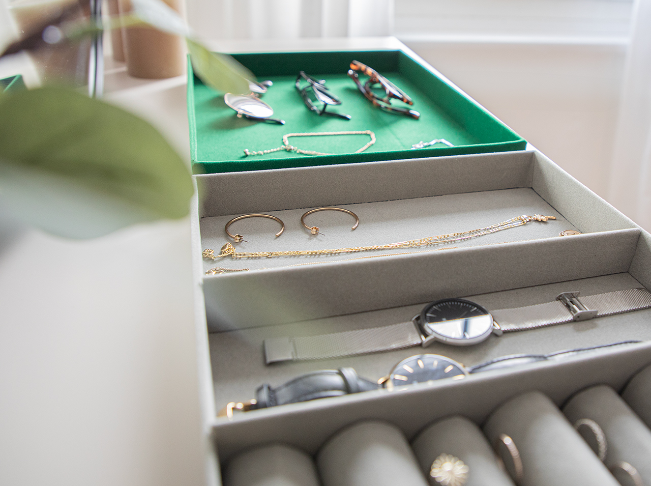 Tray for storing jewelry with inserted rings and other jewelry items on a light gray velvet surface.